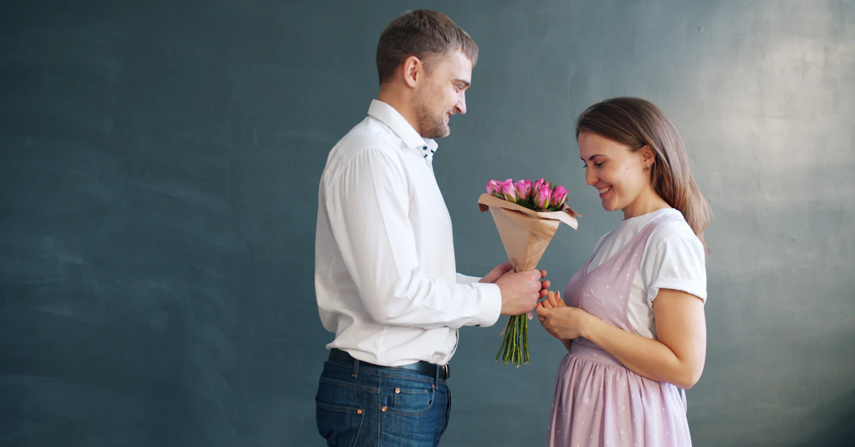 Man gives woman flowers in front of dark background