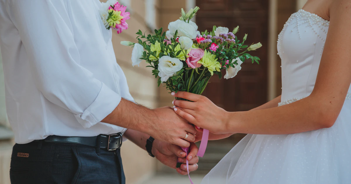 man in white dress shirt holding white and pink flower bouquet