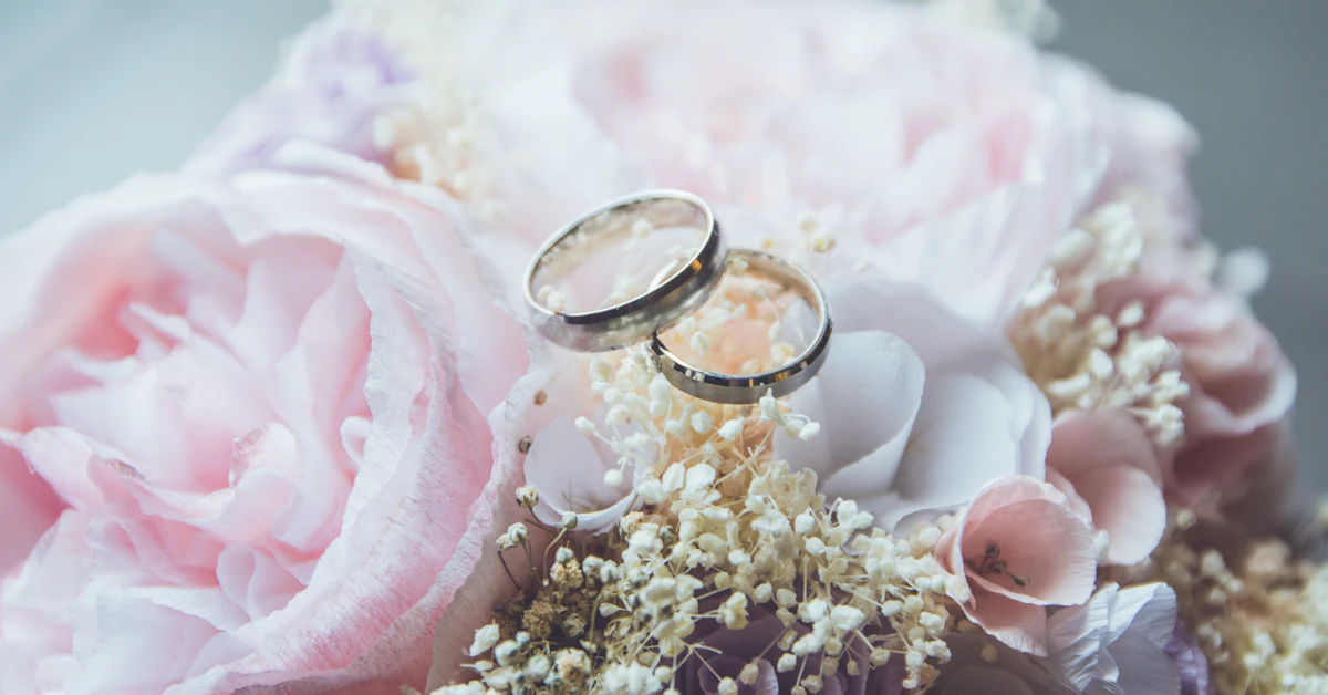 gold-colored bridal ring set on pink rose flower bouquet