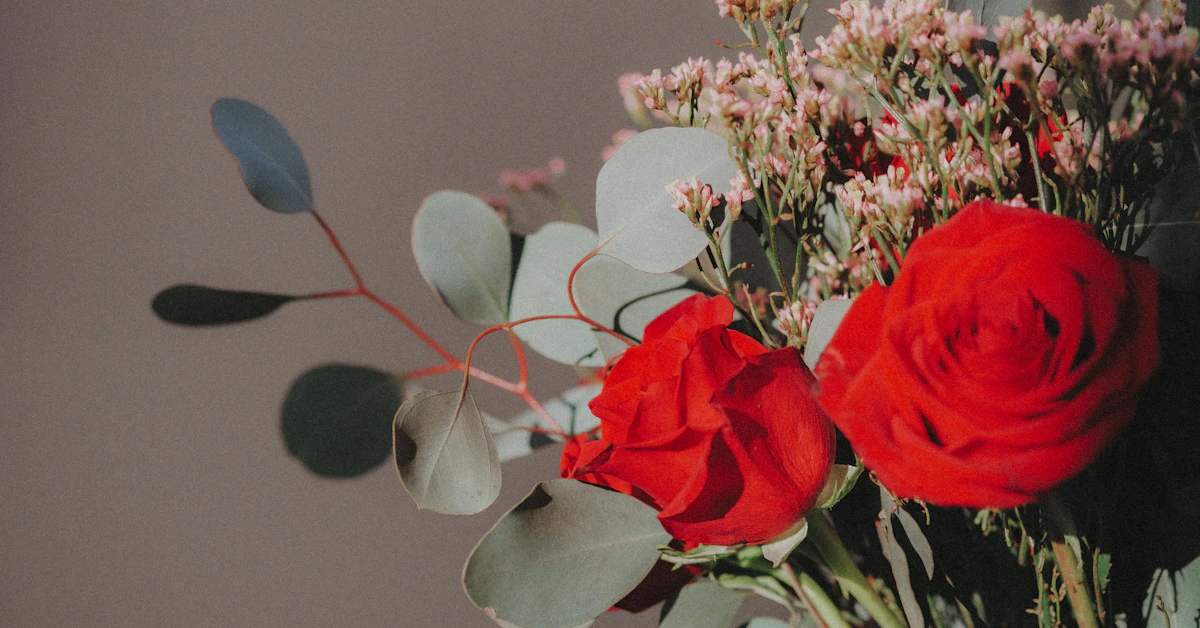 a vase filled with red roses and greenery
